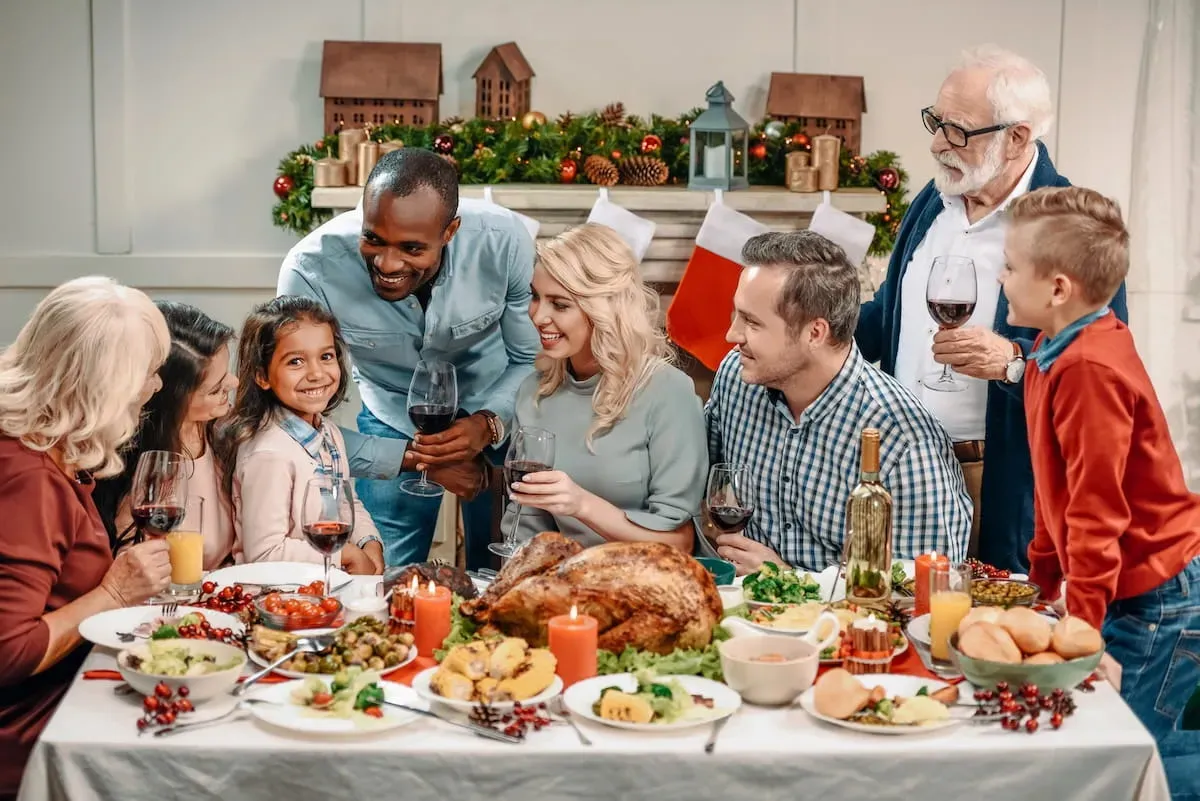 Mehrgenerationen-Familie sitzt an einem weihnachtlich gedeckten Tisch und verbringt gemeinsame Zeit