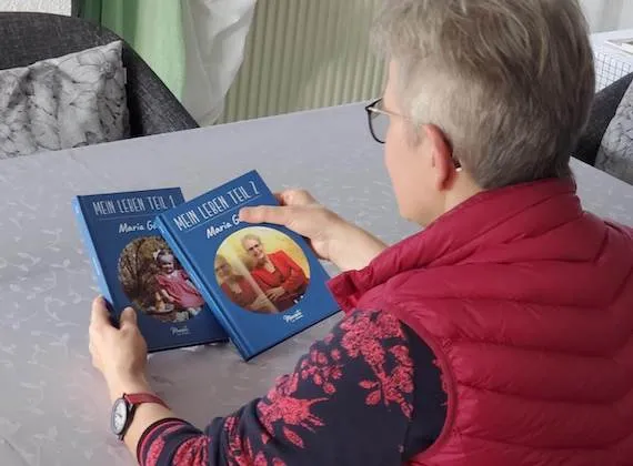Eine Meminto Kundin liest in zwei fertigen Bänden ihrer persönlichen Lebensgeschichte