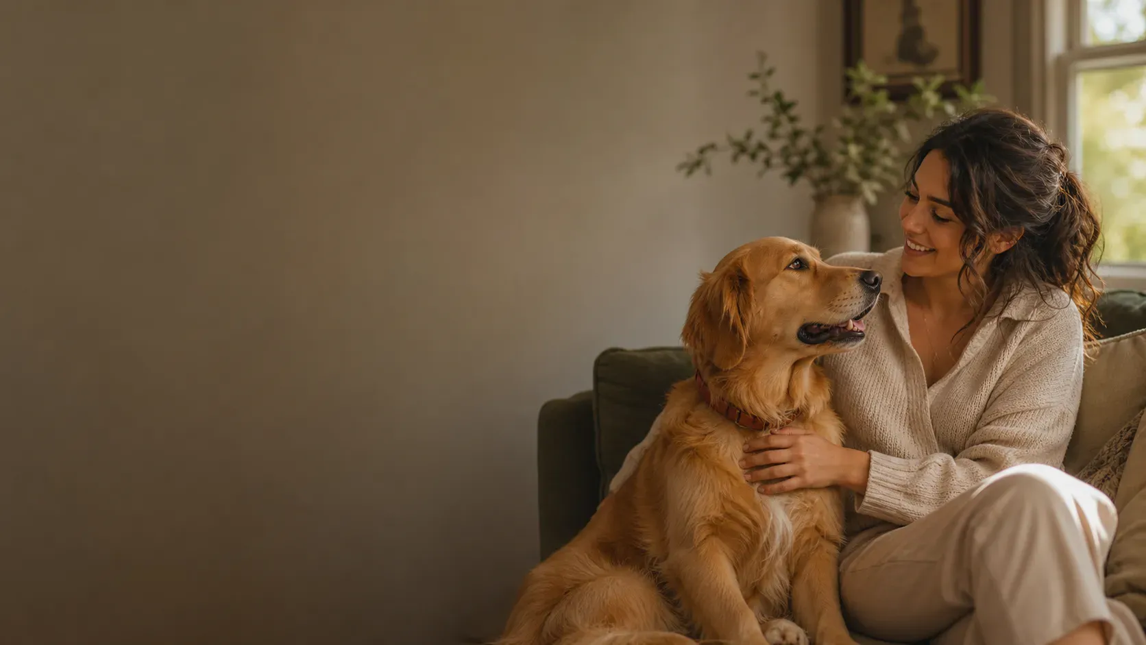 Woman sitting lovingly with her Golden Retriever on a sofa