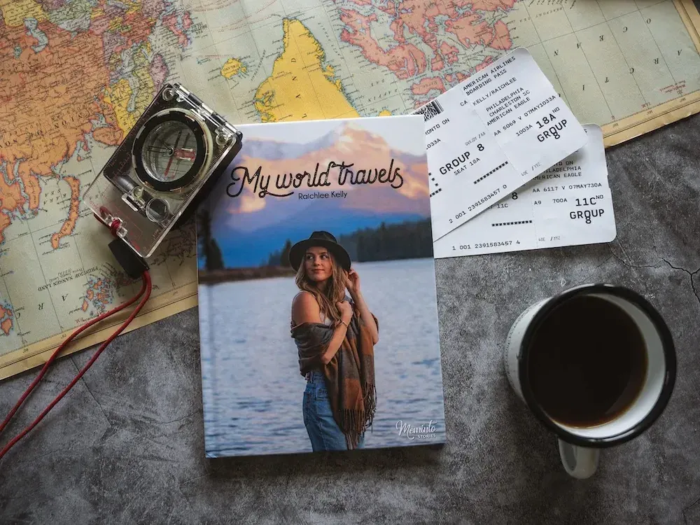 A printed Travel Book titled "My world travels" lying on a map next to boarding passes and photographs