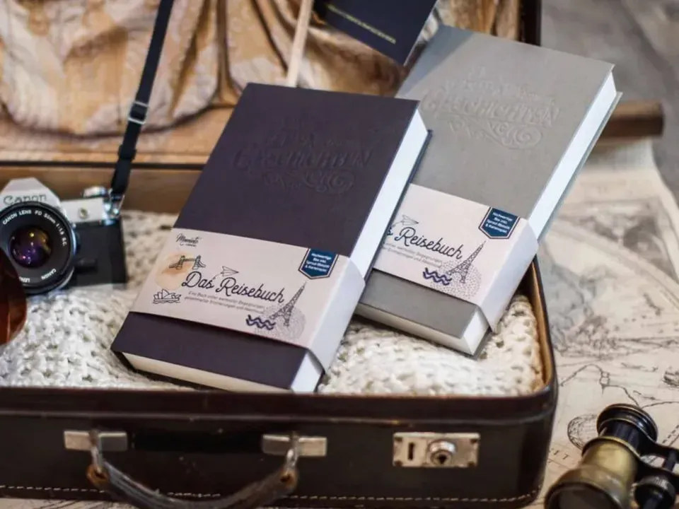 Zwei Meminto-Reisebücher in der Starter-Geschenkbox mit deutscher Banderole, verpackt in einem Vintage-Koffer