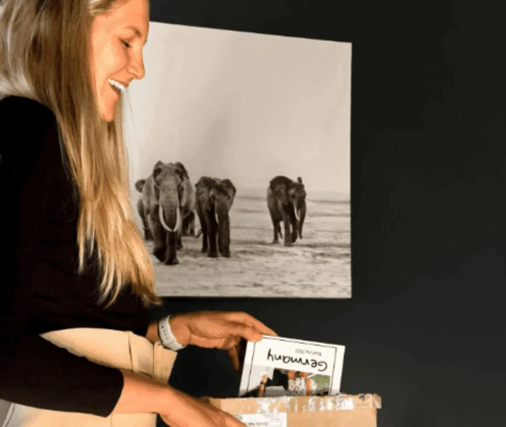 Reisende Person mit einem gedruckten Erinnerungsbuch vor einer Elefantenfotografie
