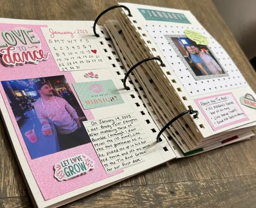 Open ring-bound scrapbook with decorated pages, photos, stickers and a handwritten dated entry