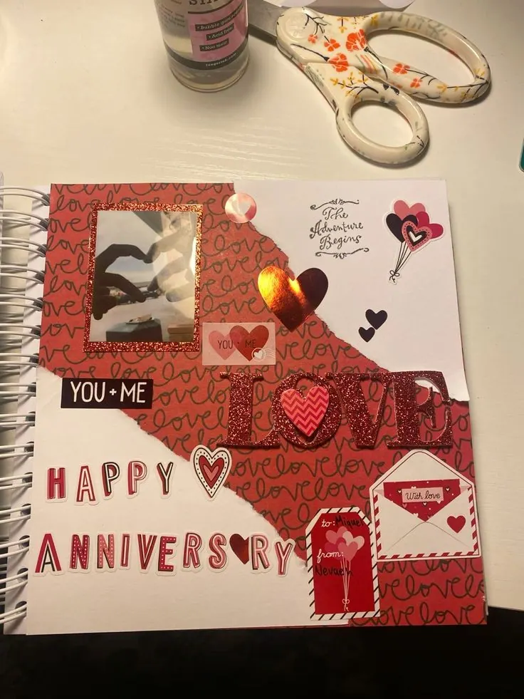Anniversary scrapbook page with heart stickers and a tiny paper envelope, scissors lying beside it