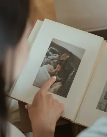 Person pointing at a photo in an open family album