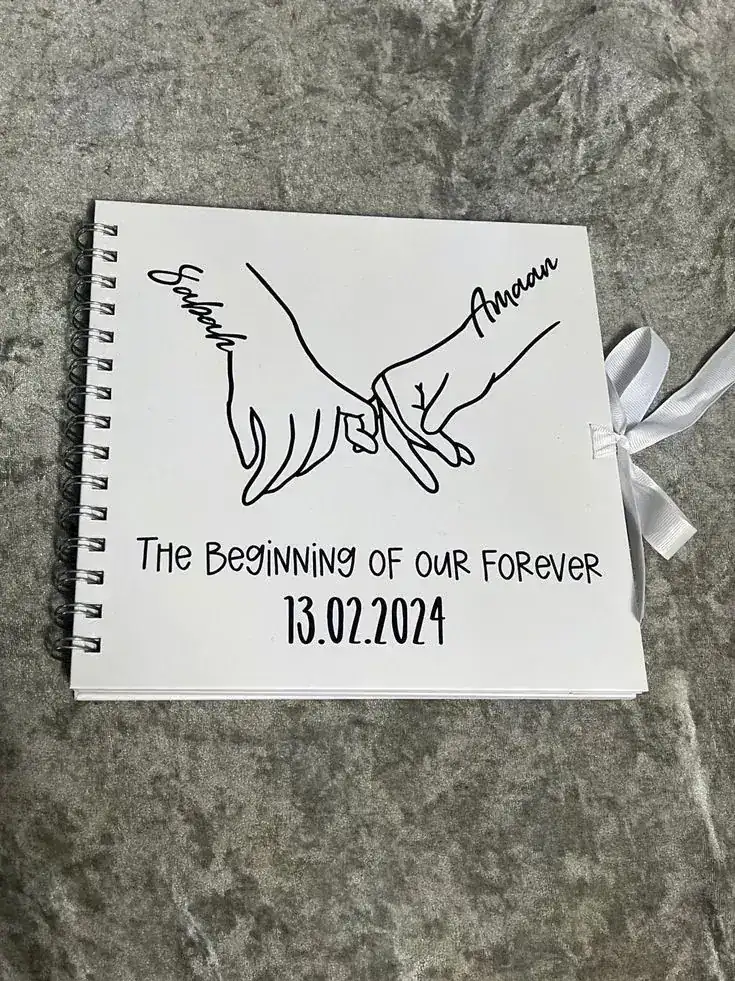Spiral scrapbook cover with a line drawing of two hands linking pinkies and a start date