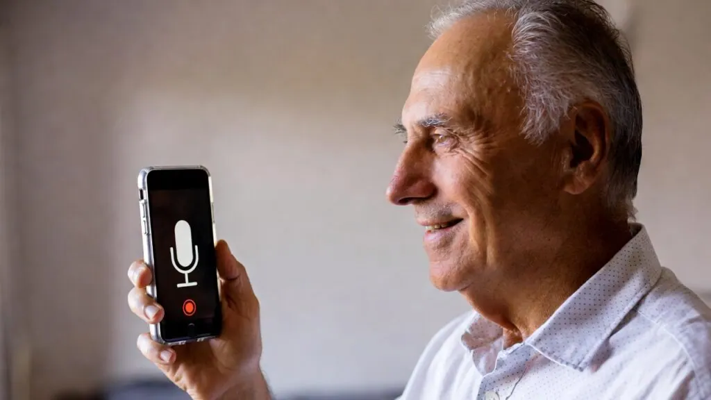 Smiling older man holding a phone with the voice recorder running