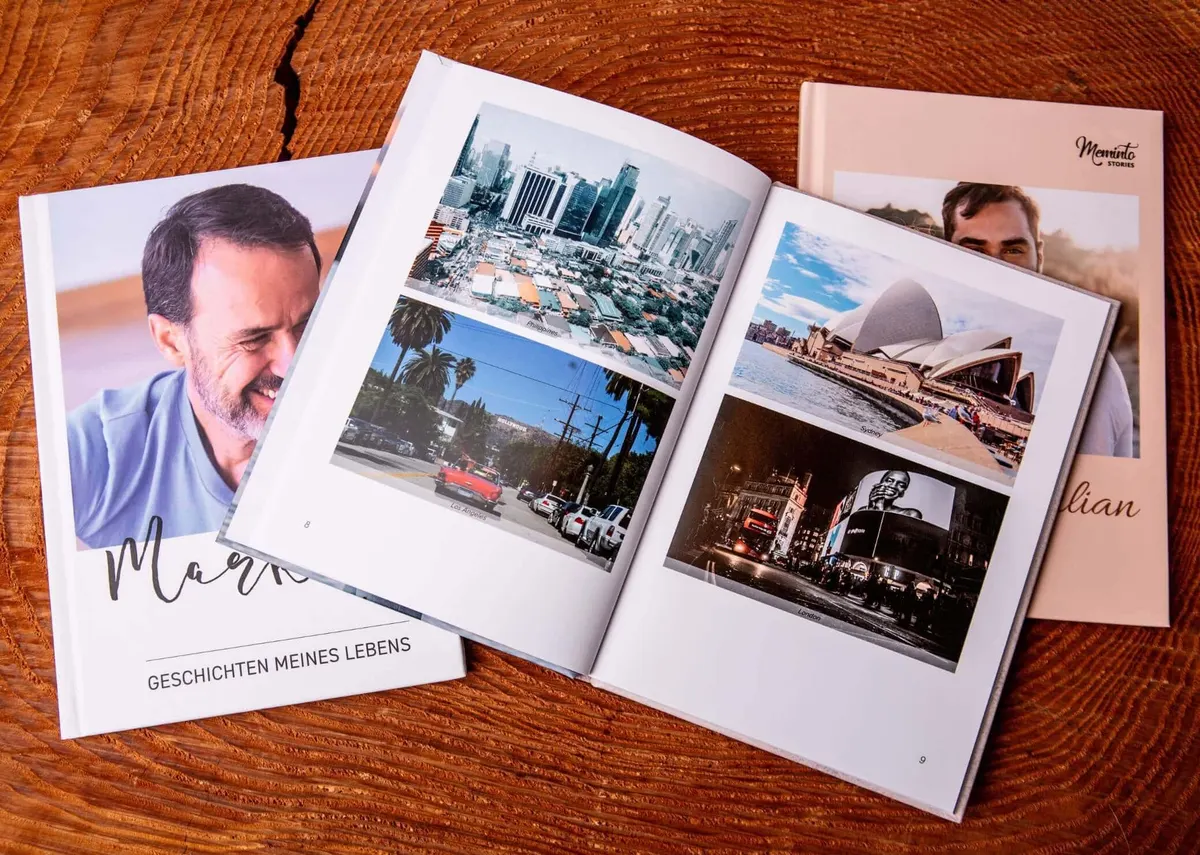 An open Meminto book with printed photos, next to two more finished books